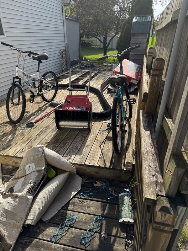 Cluttered backyard deck before removal and the cleared ground after — Before